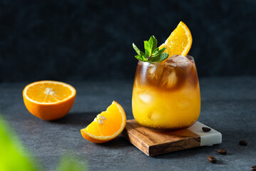 Bumble coffee with ice on a dark background. Espresso, orange juice and syrup in layers in a...