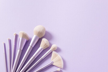 Makeup brushes set. Professional makeup tools on violet background. Set of glamour make up brushes. Magazines, social media. Visagist tools. Copy space. Creative flat lay. Cosmetics and beauty.