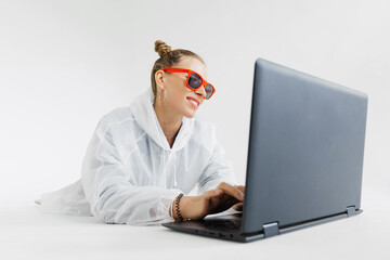 A girl is lying on the floor and looking at her laptop on a white background