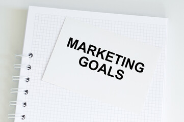 Marketing goals text on a card on the background of a notebook on the table, a business concept