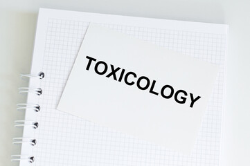 Toxicology text on a card on a white notepad on the table. Medical concept