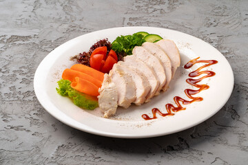 Roast chicken fillets and vegetables on gray background