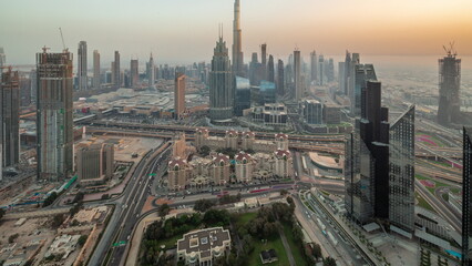 Naklejka na ściany i meble Aerial view of tallest towers in Dubai Downtown skyline and highway day to night timelapse.
