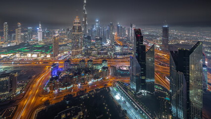 Naklejka na ściany i meble Aerial view of tallest towers in Dubai Downtown skyline and highway night timelapse.