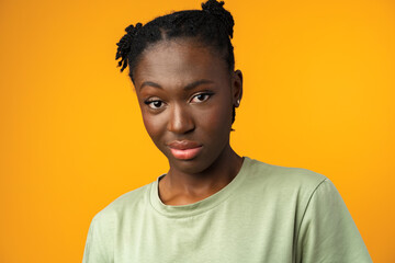 Studio shot of black girl looking suspiciously with skeptical expression in yellow studio