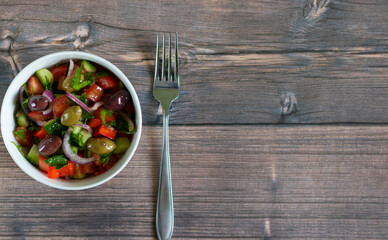 Vegetable salad with kalamata olives on wooden background with copy space