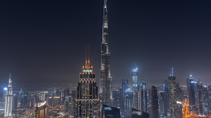 Fototapeta premium Aerial view of tallest towers in Dubai Downtown skyline and highway night timelapse.