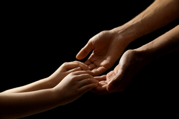Man with child on black background, closeup of hands