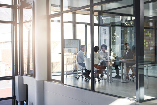 Handling their business in the boardroom. Full length shot of a group of businesspeople meeting in the boardroom.