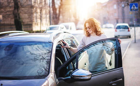 Happy Cheerful Young Woman In Sunglasses Getting Into Her Car On A City Street