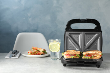 Modern grill maker with sandwiches and breakfast served on grey table