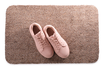 Stylish door mat with shoes on white background, top view