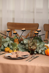Autumn table setting with eucalyptus branches and pumpkins indoors