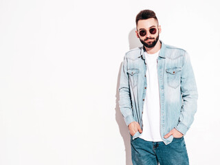 Portrait of handsome confident stylish hipster lambersexual model.Man dressed in jacket and jeans. Fashion male posing in studio in sunglasses. Isolated on white