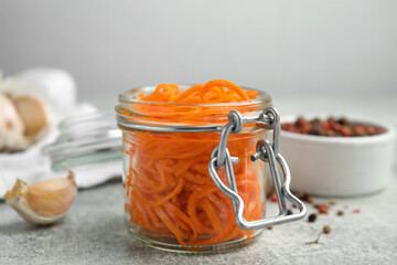 Delicious Korean carrot salad in glass jar on grey table