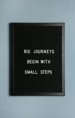 Black letter board with motivational quote Big Journey Begin with Small Steps on color background,...