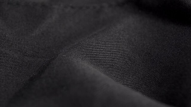 Black textured synthetic fabric. Curve texture closeup. Macro. Rotation