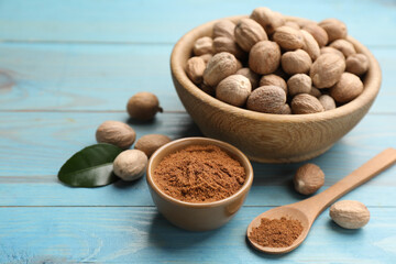 Nutmeg powder and seeds on light blue wooden table