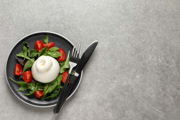 Delicious burrata salad with tomatoes and arugula served on grey table, top view. Space for text