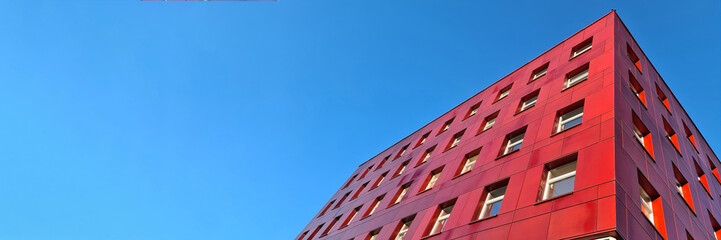 Multi-storey red building standing against blue sky background - Powered by Adobe