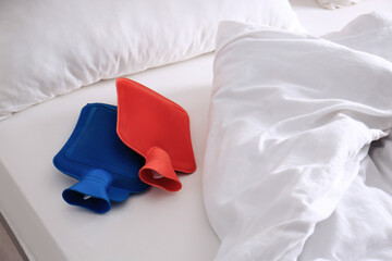 Different hot water bottles on white bed