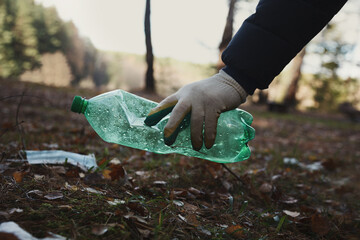 Volunteer man collecting garbage outside, picking up plastic bottle waste