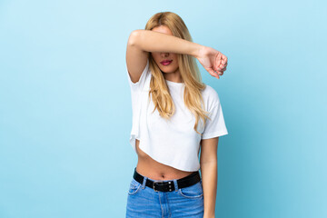 Young Uruguayan blonde woman over isolated blue background covering eyes by hands