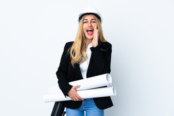 Young architect woman with helmet and holding blueprints over isolated white background shouting with mouth wide open