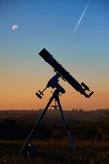 Silhouette of astronomical telescope and countryside.