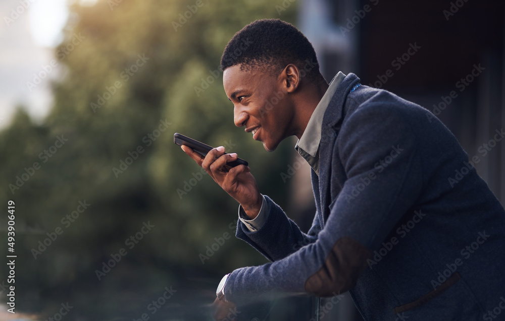 Poster Stepping outside to send some voice messages. Shot of a young businessman using a cellphone while standing on the balcony of an office.