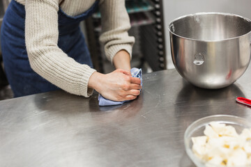 Woman cleaning work table where she is making pastry recipe in bakery