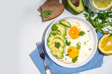 Healthy breakfast. Keto, balanced diet. Fried eggs with sliced avocado and toasts on white table background
