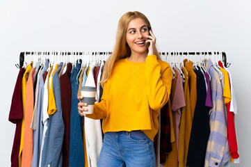 Young Uruguayan blonde woman in a clothing store holding coffee to take away and a mobile