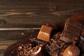 Chocolate pieces and candy on dark wooden table.