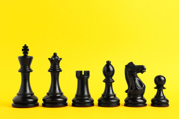 Black chess pieces on yellow background. Space for text