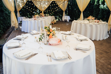 Evening decoration of a wedding party. Tables for guests with a garland and lamps