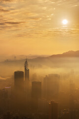 Skyscraper in downtown district of Hong Kong city in fog under sunrise