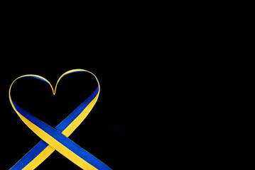 Ribbon in the color of the Ukrainian flag in the shape of a heart on a black background.