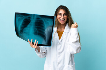 Professional traumatologist isolated on blue background celebrating a victory in winner position