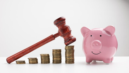 Piggy bank with wooden gavel among pile of coins