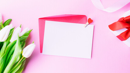 Mothers day gift. Spring white tulip flower, gift with red ribbon on flat lay pink background. Valentines, birthday, women or wedding day concept.