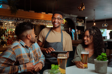 African American male waiter serving couple and friends at the restaurant