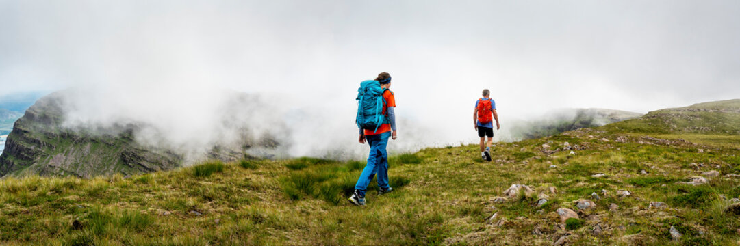 Mountain climbers with backpack walking together on grass