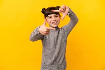 Little caucasian girl isolated on yellow background focusing face. Framing symbol