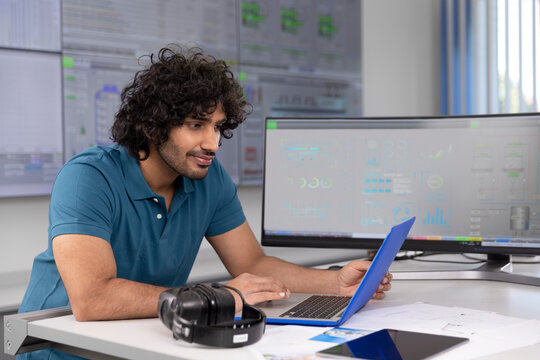 Technician using laptop at desk in control room