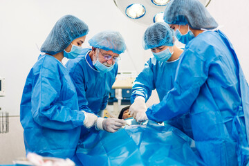 Professional anesthesiologist doctor medical team and assistant preparing patient to gynecological surgery performing operating with surgery equipment in modern hospital operation emergency room