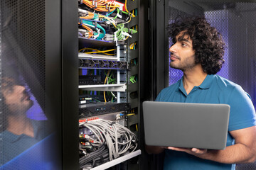 IT support holding laptop checking network server in industry