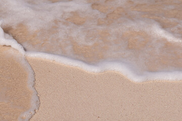 Fototapeta na wymiar Bubbles waves and sand on the beach texture background.