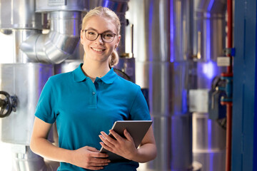 Smiling technician holding tablet PC standing in factory