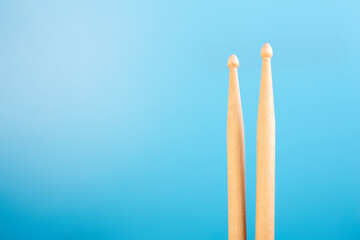 close up of drum sticks on isolated blue background. Drum lessons concept, musical instrument lessons, online drumming courses with place for text.